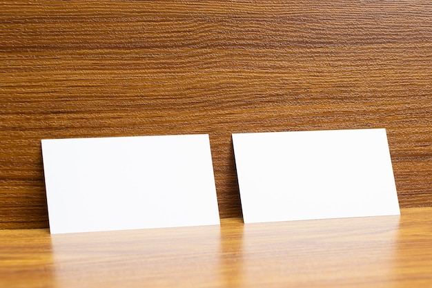 2 blank business cards locked on wooden textured desk, 3.5 x 2 inches size