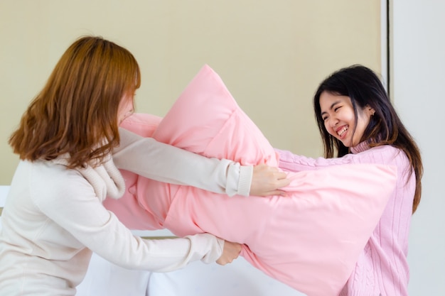 2 young women play fighting pillows