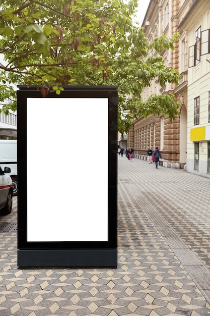 Free photo 3d illustration. vertical billboard with mock up place for your advertisement against city space. blank advertising stand. public information board over urban setting. display box. cityscape