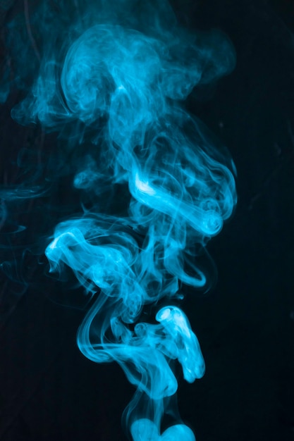 Abstract of blue smoke fumes moving upward on black background