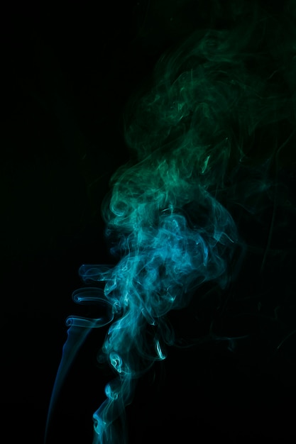 The abstract pattern made from blue and green smoke rising from an incense stick