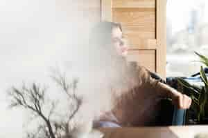 Free photo abstract scene of a reflected tree and a girl looking through the window