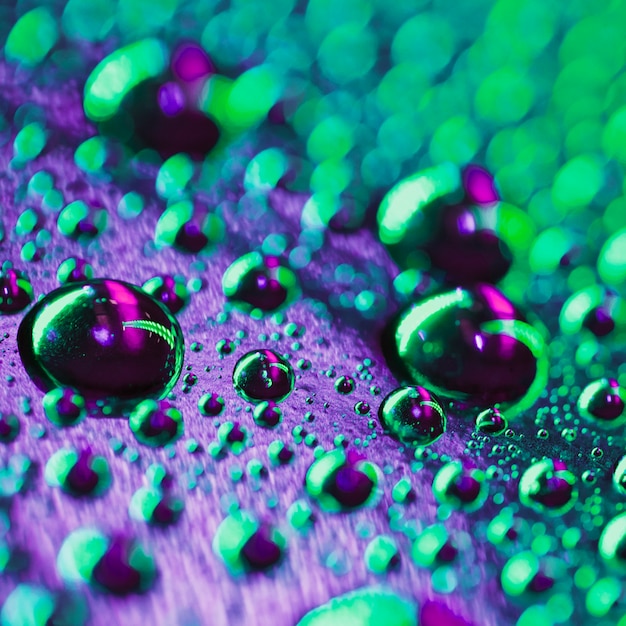 Free photo abstract water drops on transparent purple and green glass background