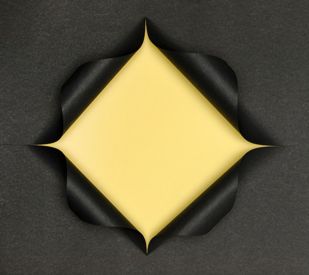 Free photo abstract yellow shape on torn black paper