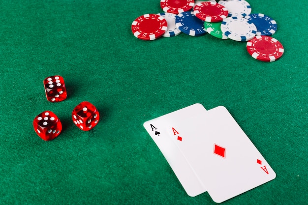 Ace playing cards; dice and chips on green poker table