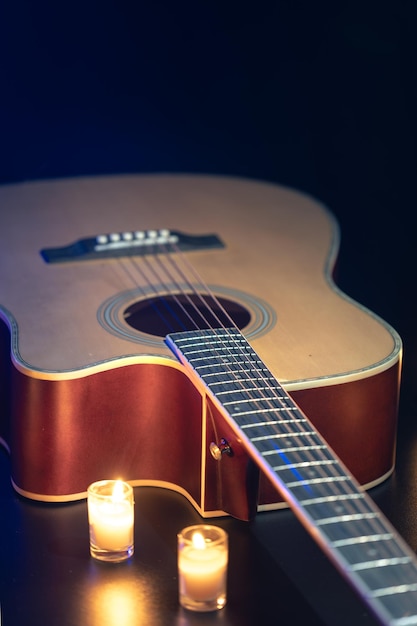 Free photo acoustic guitar on a black background with candles