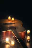 Free photo acoustic guitar on a black background with candles