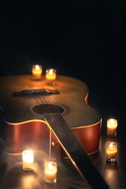 Acoustic guitar on a black background with candles