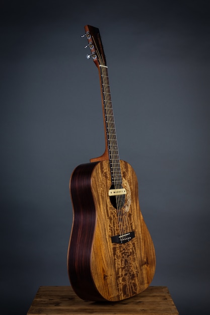 Acoustic guitar on a chair in black wall.