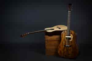 Free photo acoustic guitar on a chair and close-up brown guitar in black wall.