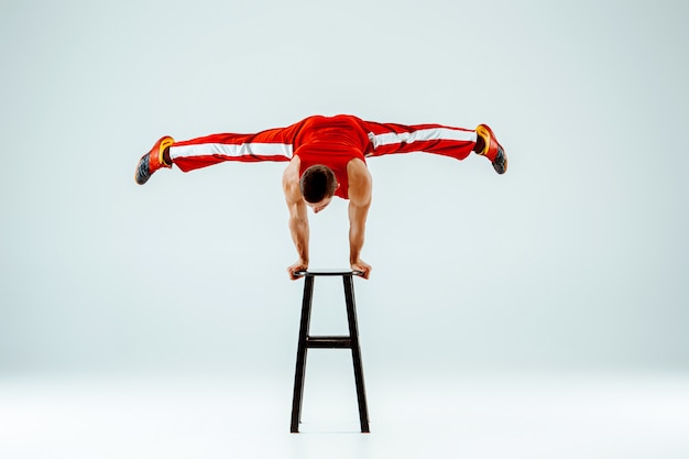 Free photo acrobatic man on balance pose on a stool