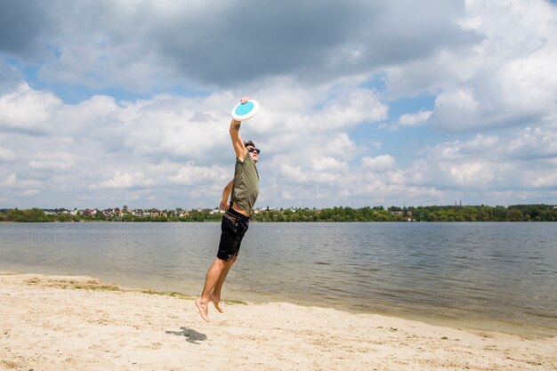 Active male playing frisbee on sandy beach