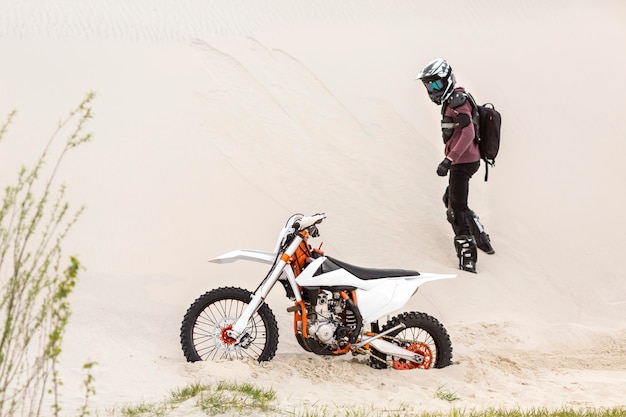 Free photo active rider watching his motorbike in the desert