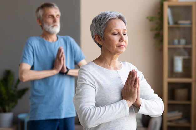 Active senior people doing yoga at home