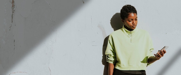 Free photo active woman using a phone by a white wall