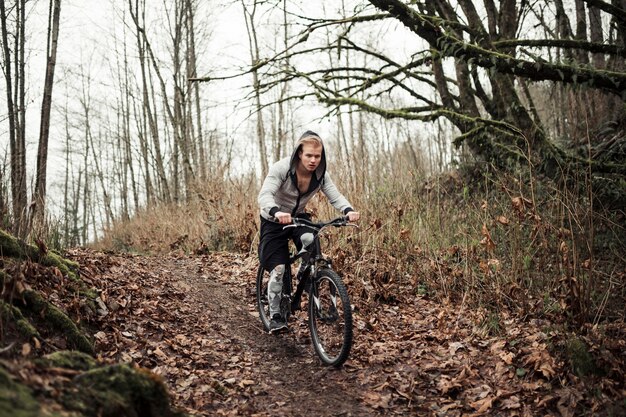 Active young man riding bicycle in the forest