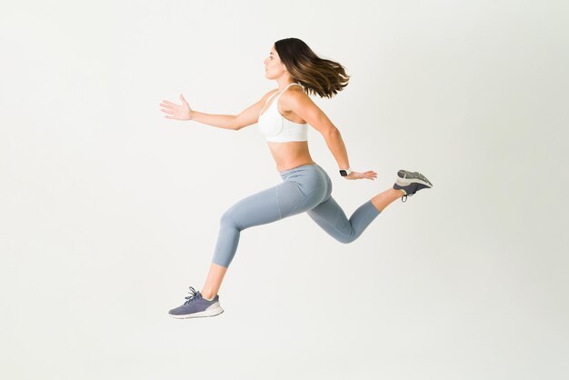 Active young woman in sportswear jumping in the air. Sporty female athlete with a strong resistance doing a cardio workout and HIIT training