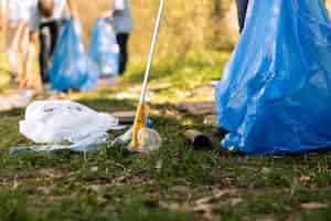 Free photo activist using claw tool to collect rubbish and plastic junk from the ground