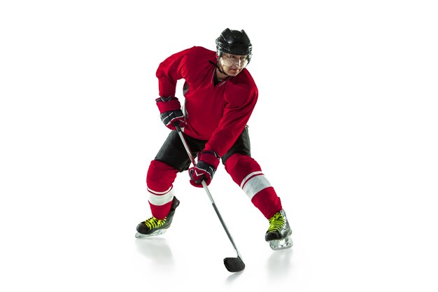 Activity. Male hockey player with the stick on ice court and white wall. Sportsman wearing equipment and helmet practicing. Concept of sport, healthy lifestyle, motion, movement, action.