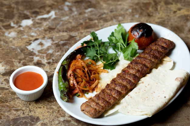 Free Photo adana kebab served with flatbread, grilled pepper and tomato and caramelized onion