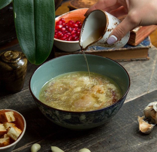 Adding broth into chicken soup in a blue authentic bowl