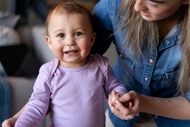 Adorable baby being held by his mother and sitting on the floor