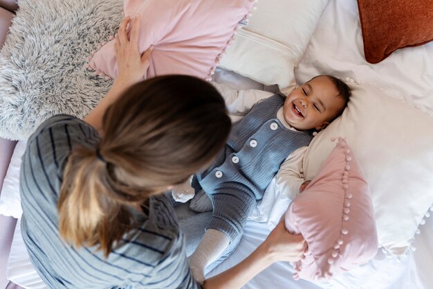 Adorable baby laughing and playing with his mother on bed