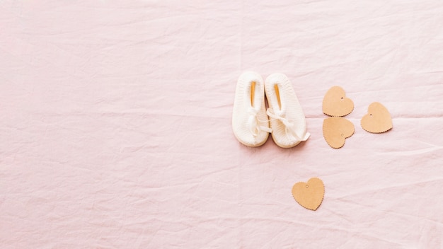 Free photo adorable baby-shoes and paper hearts