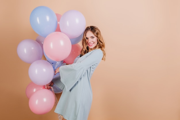 Free photo adorable blonde white woman in blue attire posing with beautiful balloons