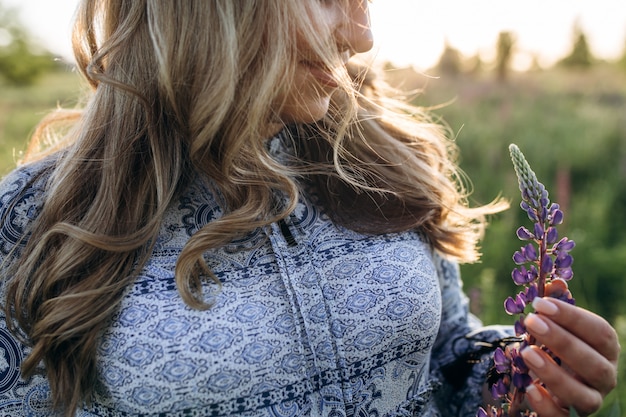 Free photo adorable blonde woman in blue dress walks across the field of violet lavender flowers