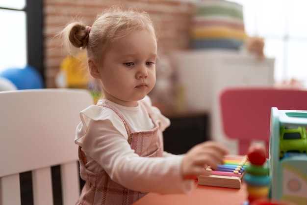 Free photo adorable caucasian girl playing with toys sitting on table at kindergarten