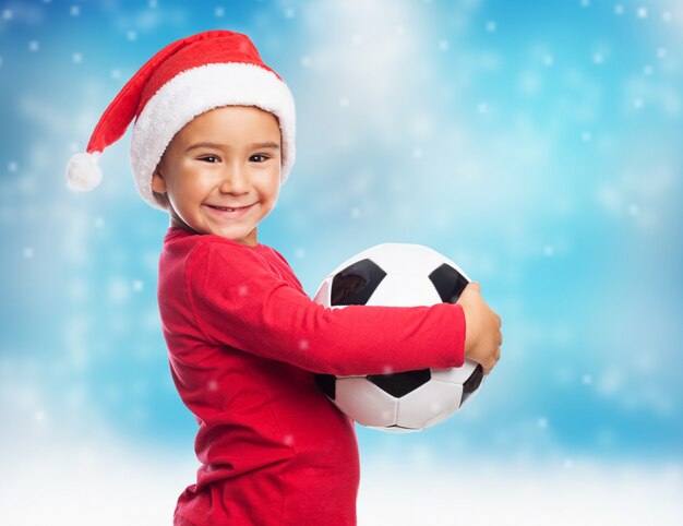 Adorable child with santa hat showing his ball