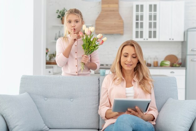 Adorable daughter offering flowers to her mother