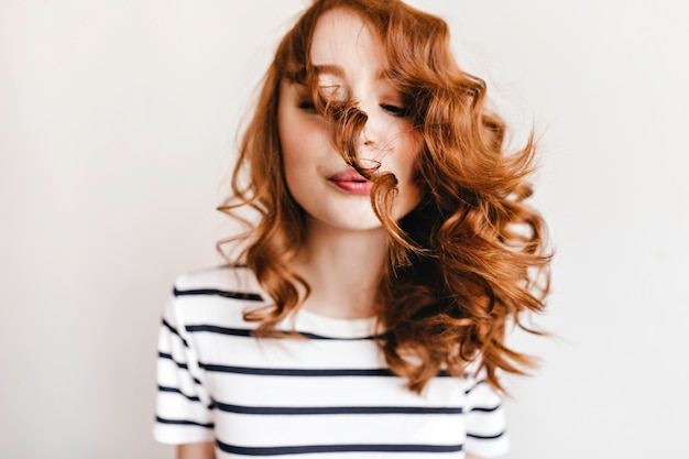 Free photo adorable ginger woman blowing on her curly hair. joyful caucasian lady.