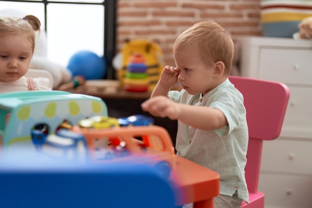 Free photo adorable girl and boy playing with toys on table at kindergarten