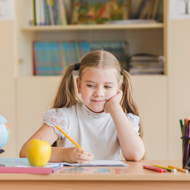 Free photo adorable girl looking at apple during lesson