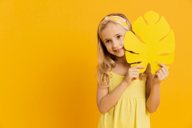 Free photo adorable girl posing with leaf and copy space