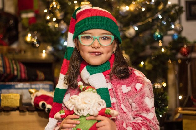 Free photo adorable girl smiling and holding her santa claus toy