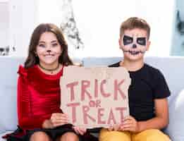 Free photo adorable kids holding trick or treat sign