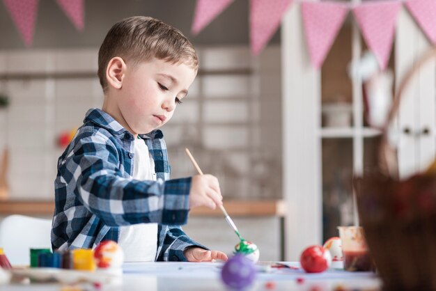 Adorable little boy painting eggs for easter