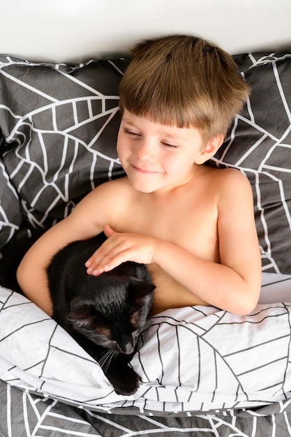 Adorable little boy petting his cat