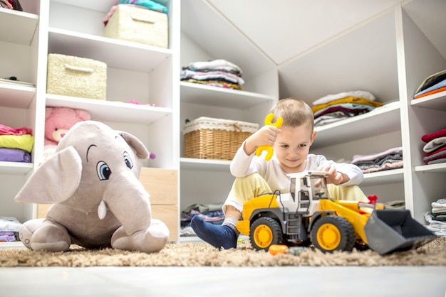 Free Photo adorable little boy playing with toys while sitting on the floor in his playroom