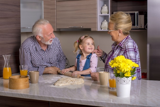 Adorable little girl cooking with her grandparents