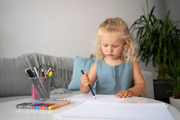 Adorable little girl drawing on paper at home