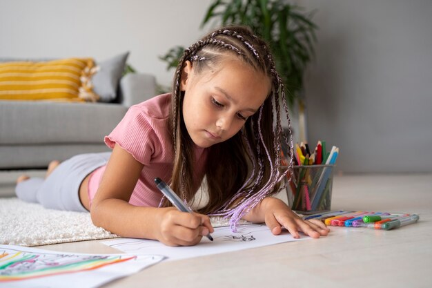 Adorable little girl drawing on paper at home