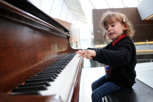 Free photo adorable little girl having fun playing the piano