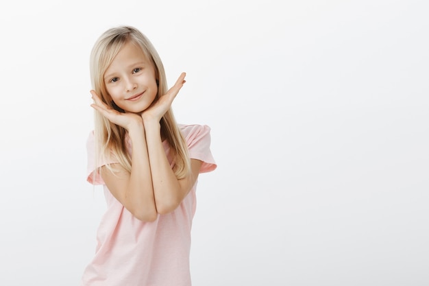 Adorable little girl holding hands over face, looking happy