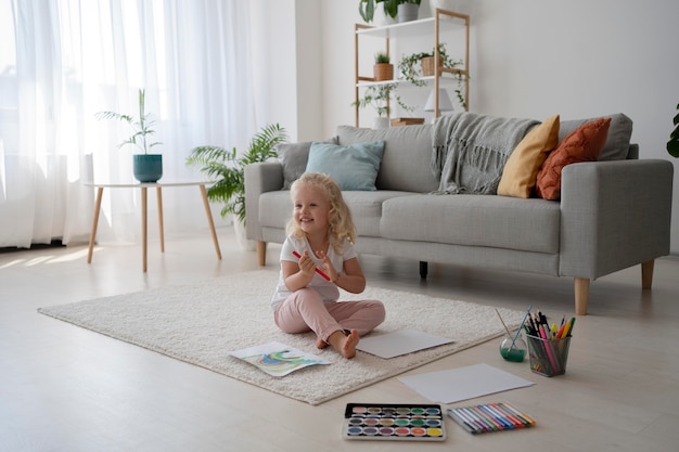 Adorable little girl painting on paper at home