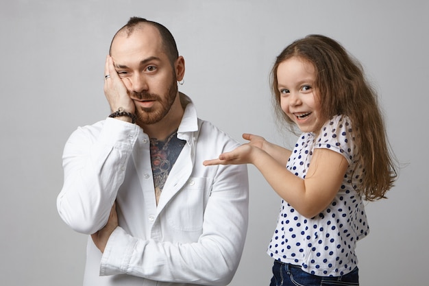 Adorable little girl with loose dark hair laughing, looking at camera with joyful smile, having fun in studio