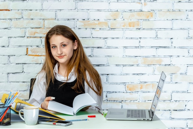 An adorable student sitting behind the desk and looking at the camera High quality photo